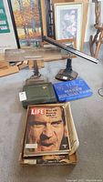 Image showing two vintage adjustable desk lamps, a green Craftsman hair clipper case, blue Marbo shoe shine holder box and Life magazines in a cardboard box.