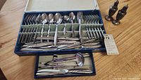 Full set of Stonegate stainless steel flatware items including forks, spoons, knives, and serving utensils displayed in original box and set included salt and pepper shakers.