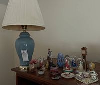Overall view of the table lamp, miniature figurines under glass domes, and other small decor on wood cabinet
