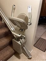 Front angled view of the stair lift chair on track installed on staircase.