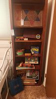 General view of wooden shelving unit filled with assorted vintage board games and card game boxes including Chinese Checkers, Bingo, Trivial Pursuit, Roulette, Scrabble