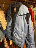 Light blue padded winter jacket hanging on rack