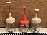 Front view of three vintage food choppers on a counter with textured background.