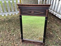 Full view of beveled framed mirror showing overall design and condition outdoors against grass and fence.