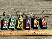 Top view of six mummering wooden Christmas ornaments laid out in a row next to a ruler for scale