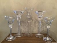 Front view of 5 Bohemia crystal candlestick holders: two shorter broad-topped, two taller twisted-stem, one tallest wide cup top