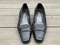 Top view showing the front and upper design of the black leather wedge heels with square toes and stitching detail.