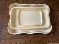 Three French Ivory vanity trays stacked showing size gradient and shape, on wooden surface.