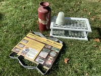 Overview of the lot showing all items placed on grass including metal shoe rack, molds, fire extinguisher, and glass insulator.
