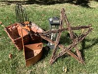 Photo showing planter basket with black wire back and orange deer figurine, twig star, lantern, and orange metal scoop on grass.