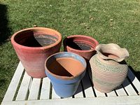 Front angled photo of four garden terra cotta planter pots showing size and color variations