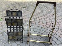 Photo showing black metal folding magazine stand with decorative panels and vintage metal TV tray stand with bronze frame and brown plastic parts.