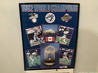 Full view of framed 1992 Toronto Blue Jays World Champions poster showing multiple images of players, logos, Canadian flag, and trophy.