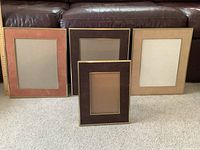 Four vintage velour picture frames arranged on carpet with a brown leather sofa behind them