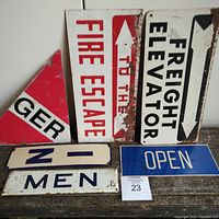 Photo showing all 6 assorted signs together on wooden surface including FIRE ESCAPE, FREIGHT ELEVATOR, MEN, IN, OPEN/CLOSED, and partial triangular sign.