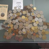 Top-down view showing multiple coins spread out including an Australian half penny in original card packaging and various loose coins.