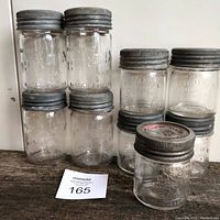 Nine vintage Corona and Crown sealer jars on wooden surface, showing two tiers of jars with metal lids.