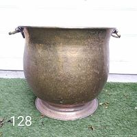 Front view of large brass planter showing rounded body, flared rim, and patina.
