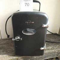 Black Koolatron mini fridge closed showing front door with small window, silver handles and top handle for portability