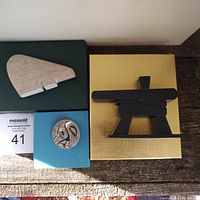 Lot of three items: carved stone polar bear on a green box, pewter brooch in original blue box, carved wooden Inukshuk sculpture on yellow box.