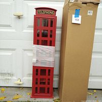 Full view of the red British phone booth style CD rack next to its cardboard box with missing top flap.