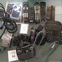 Full view of assorted electronics including remotes, mini keyboards, Roku device, cables, battery charger, and power adapters.