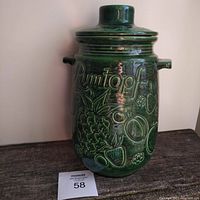 Front view of green glazed Rumtopf canister showing embossed fruit patterns and handles