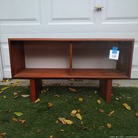 Front view of the teak veneer hutch top showing open compartment and glass door section on right side, supported by four legs.