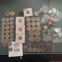 Overview of all coins laid out on table including bagged small denominations, loose coins and mounted pieces