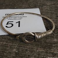 Top view of the round sterling silver bracelet showing coil detail and clasp, along with auction lot tag.