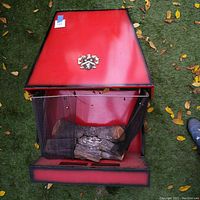 Top view of the vintage wall mount electric fireplace showing red metal body, mesh screen, faux logs, and decorative crest.