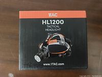 Box front view showing 1TAC HL1200 Tactical Headlamp branding and website.