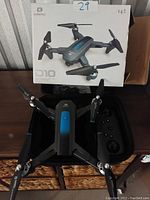 Deerc D10 drone with foldable arms and propellers, blue and black color, with packaging box in background