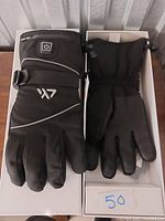 Pair of black heated gloves displayed side by side showing front and back of gloves, power button visible on one glove.