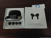 Photo of Tranya T30 Game Mode wireless earbuds package with charging case, USB cable, and four extra ear tips shown inside the package