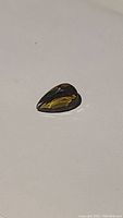 Pear-shaped champagne colored citrine gemstone on white background showing facets and color