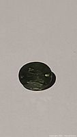 Close-up photo of a natural green sapphire oval cut gemstone showcasing its color, cut, and inclusions.