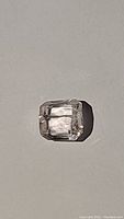 Natural untreated kunzite gemstone emerald cut, viewed from front with facet reflection visible.