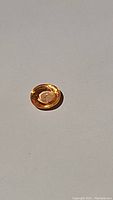 Oval cut yellow-orange sapphire gemstone lying on white surface showing bright, vibrant color and cut faceting.