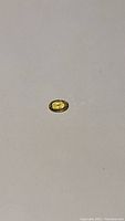 Oval cut natural yellow-green sapphire on a plain white background, showing color and size.
