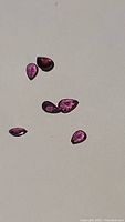 Six pink garnet gemstones laid on a flat surface, showing their size and color variation.