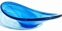 Side view of the mid century asymmetrical blue art glass bowl showing its elongated, curved profile with one edge higher than the other.
