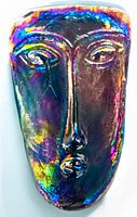 Front view of iridescent mid century art glass face sculpture showing stylized facial features with multicolored reflective finish.