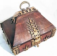 View of trapezoidal wooden box with brass detail showing top and front latch