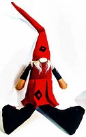 Frontal image of the Swedish gnome Santa doll showing the long red pointed hat and black and red outfit with mittens and large black legs.