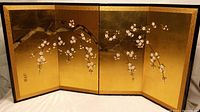 Front view of the folded gold leaf table screen with cherry blossom branch painted across four panels.