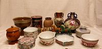 Front view of collection of various Asian ceramics and decor items arranged together showing variety in size and shape.