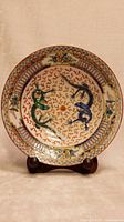 Full view of the round porcelain plate showing two dragons in the center, one green and one blue, surrounded by decorative patterns