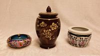 Photo showing the three pottery items together: cloisonné ashtray, brown lidded pot, and small painted flower pot.