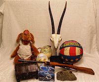 View of the lot showing all items including the basketball, oryx skull, chest, pop toy, pyrite candlestick holder, mini laser light, and rifle replica.